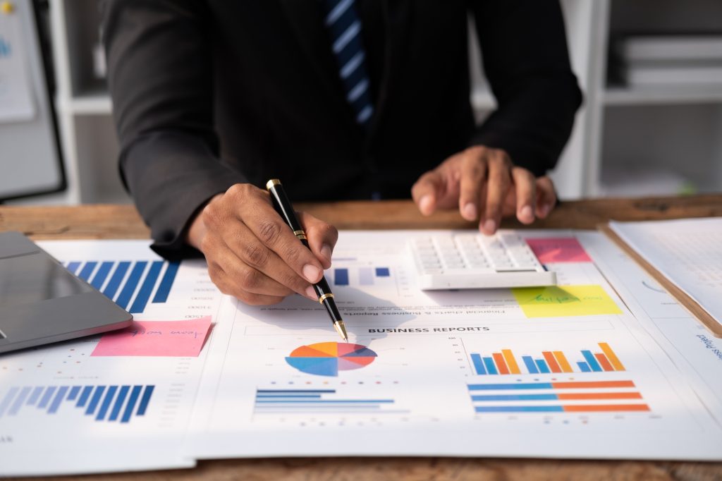 Close up view of young smart businessman analysing the investment strategy in office room.